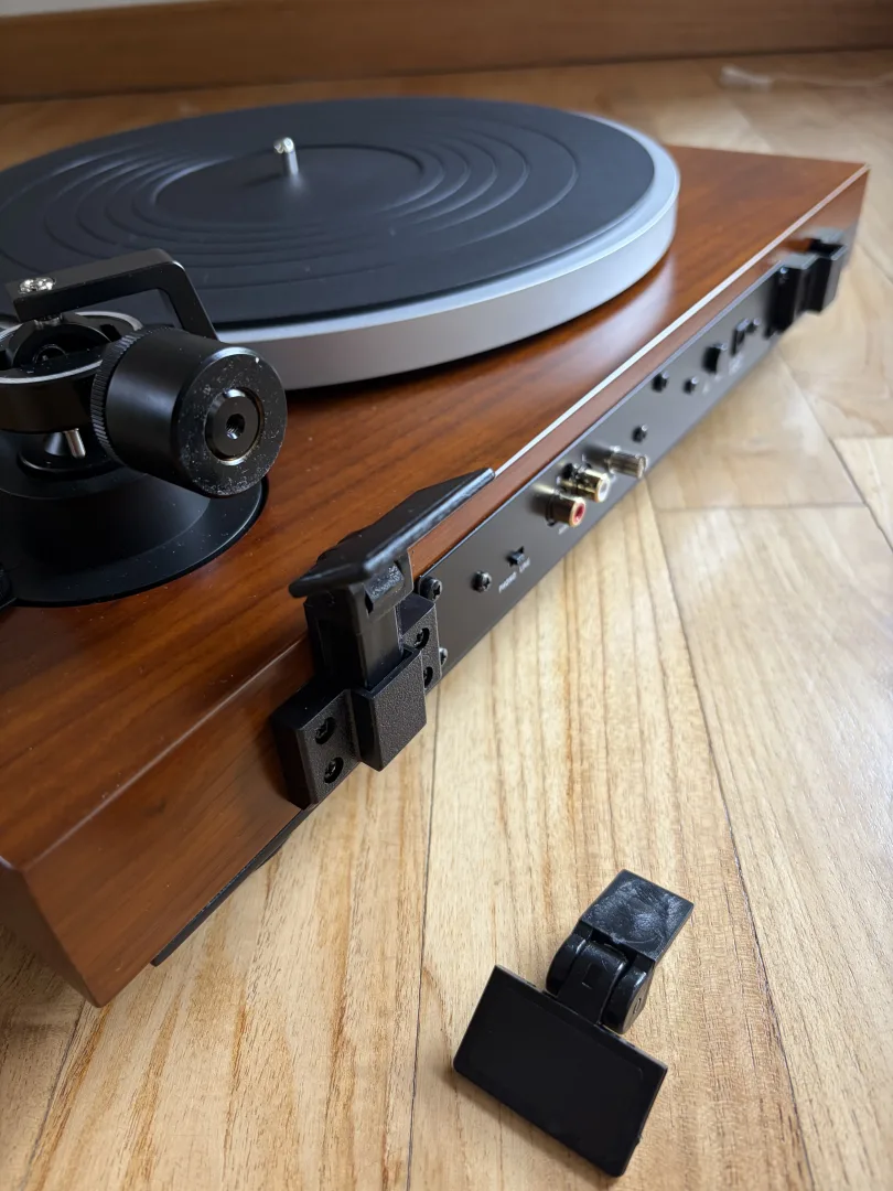 Arrière de la platine Dual CS 529 BT avec l'emplacement de fixation du capot et une pièce de fixation posée au sol
