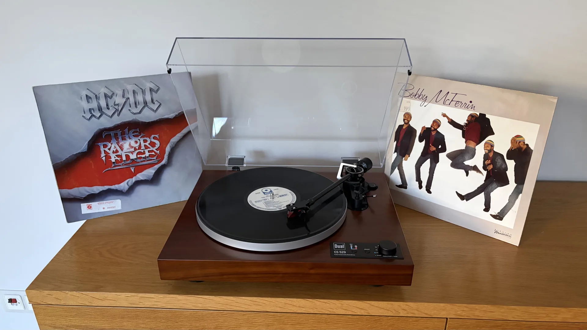 Platine vinyle Dual CS 529 BT avec un disque sur le plateau, entre deux pochettes de vinyles