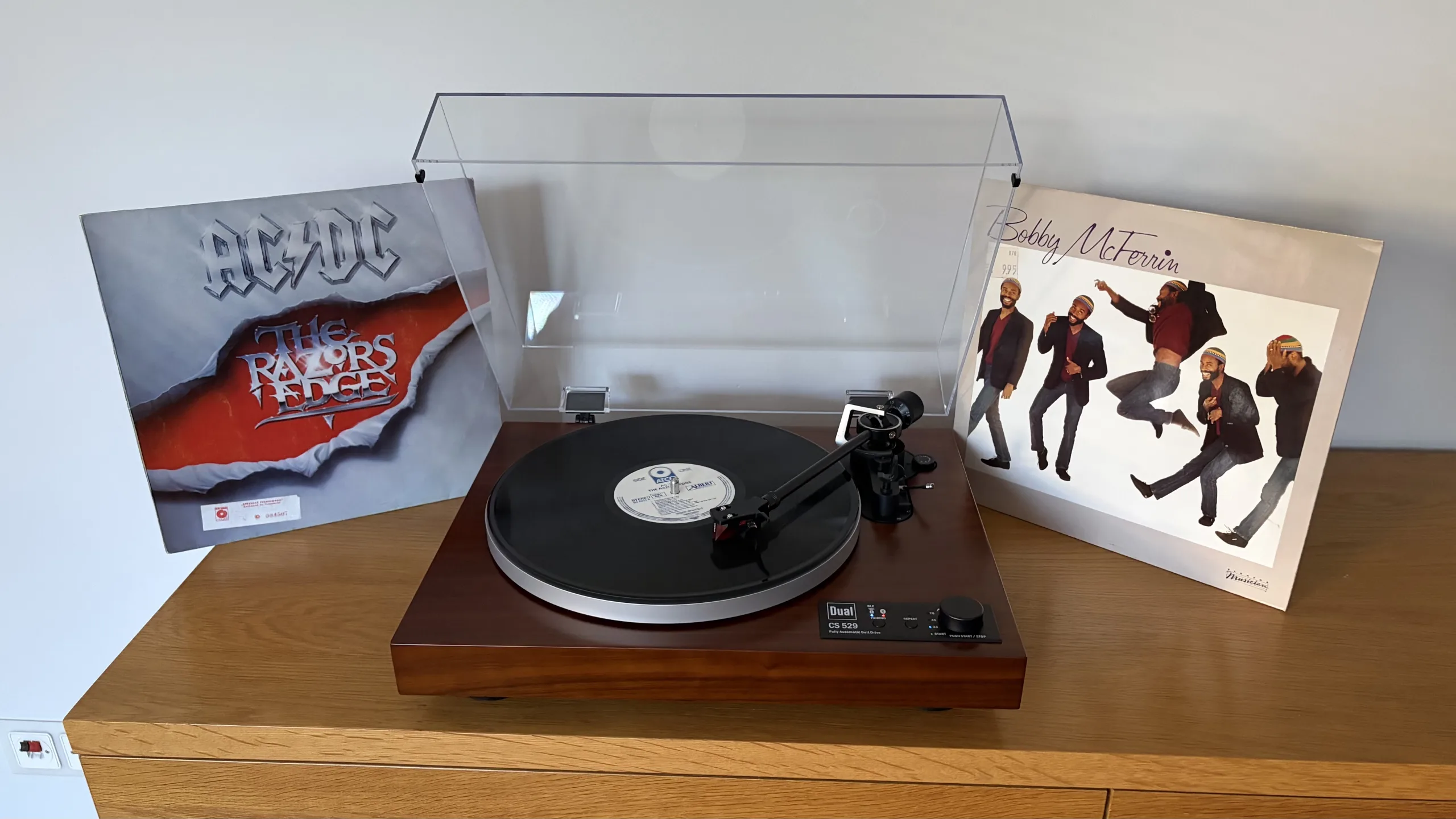 Platine vinyle Dual CS 529 BT avec un disque sur le plateau, entre deux pochettes de vinyles