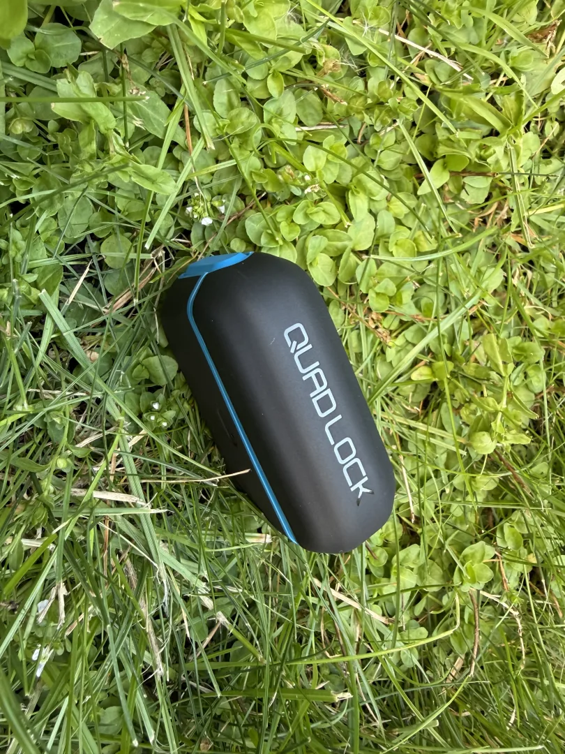 Coque posée dans l'herbe, vue de profil avec le logo Quad Lock