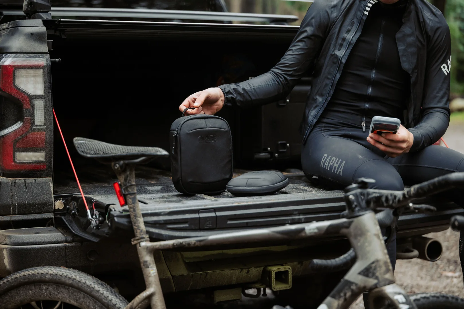 Quad Lock Travel Organiser Medium et Large posés sur le hayon d'un pick-up lors d'une sortie vélo