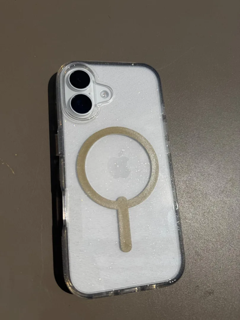 Coque ZAGG Milan Snap Glitter Gold posée sur une table, vue de la double caméra et de l'anneau MagSafe doré